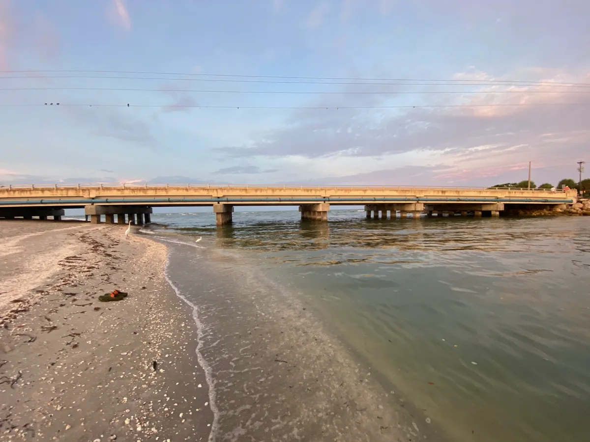 Sanibel Causeway bridge over calm waters with sandy beach in foreground
